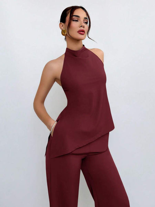 Vista frontal de una mujer usando un conjunto elegante de dos piezas color burdeos con top halter y pantalón recto.