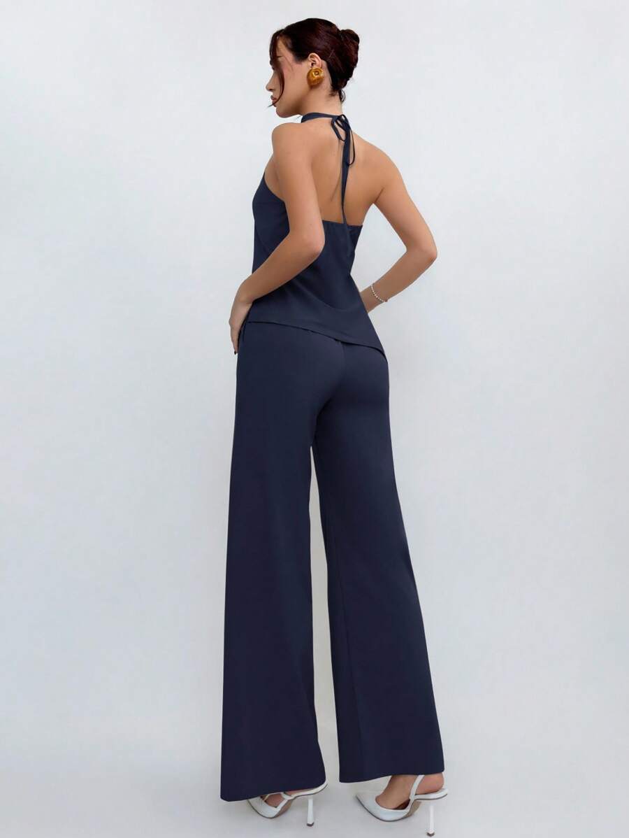 Mujer vistiendo un conjunto de dos piezas azul marino con top halter y pantalón de pierna ancha.