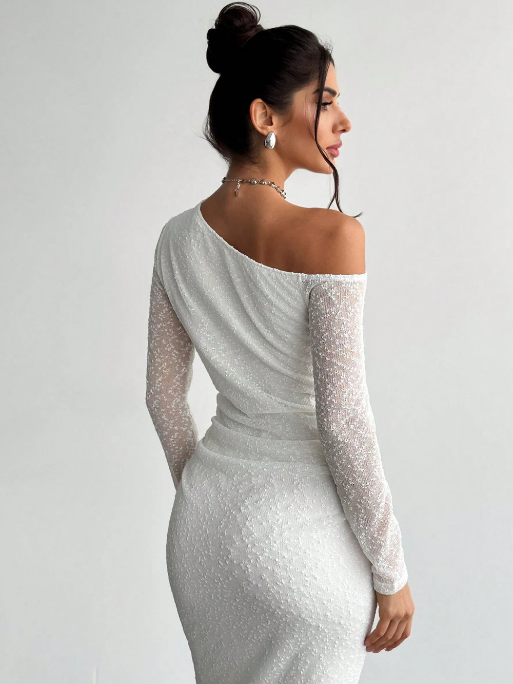 Detalle del escote asimétrico y fruncido del vestido blanco elegante.