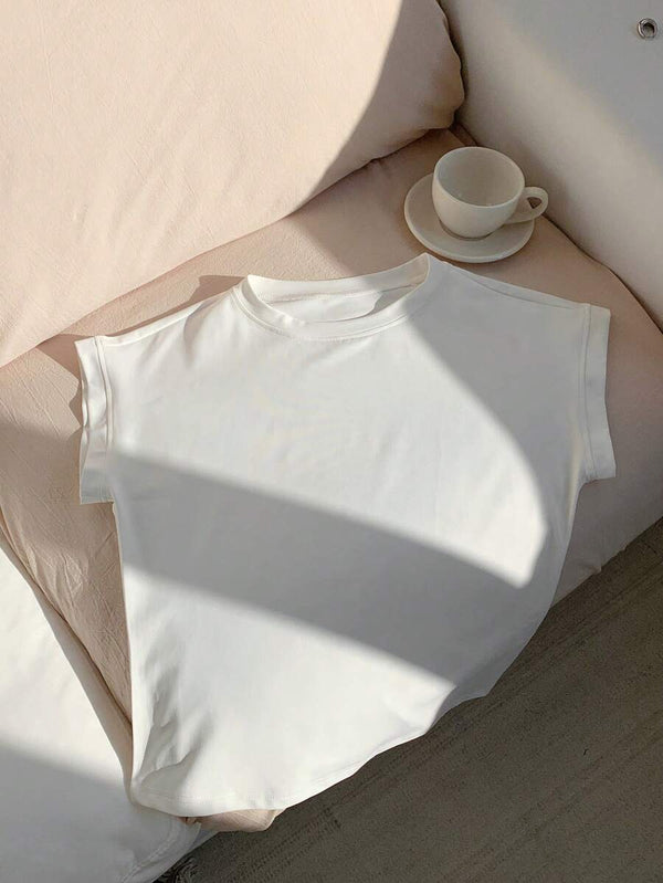 Blusa blanca casual con manga murciélago sobre cama