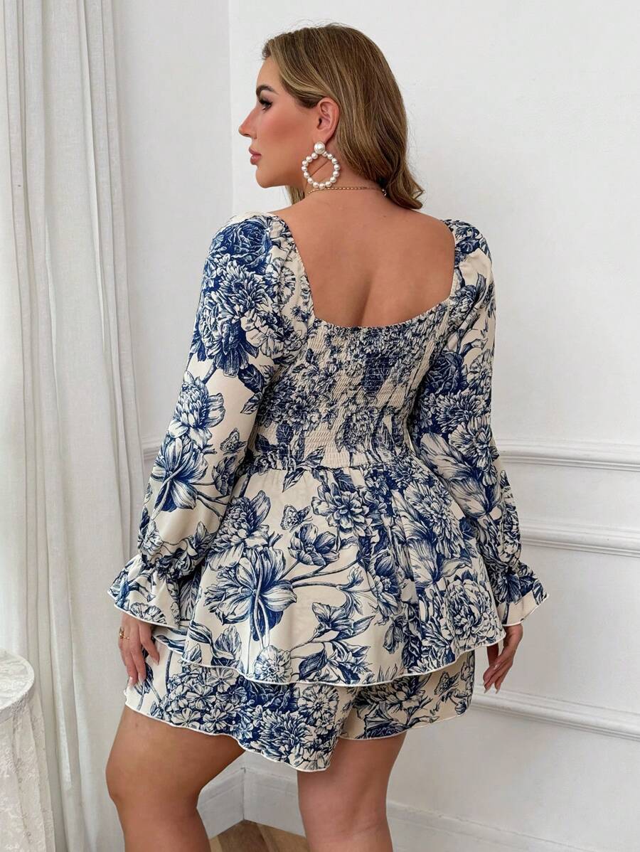 Mujer de talla grande posando con un romper floral azul y blanco de manga larga y escote corazón.