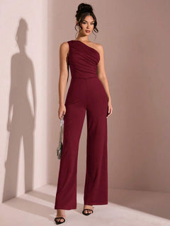 Mujer modelando un jumpsuit elegante color vino de un solo hombro con detalle drapeado.