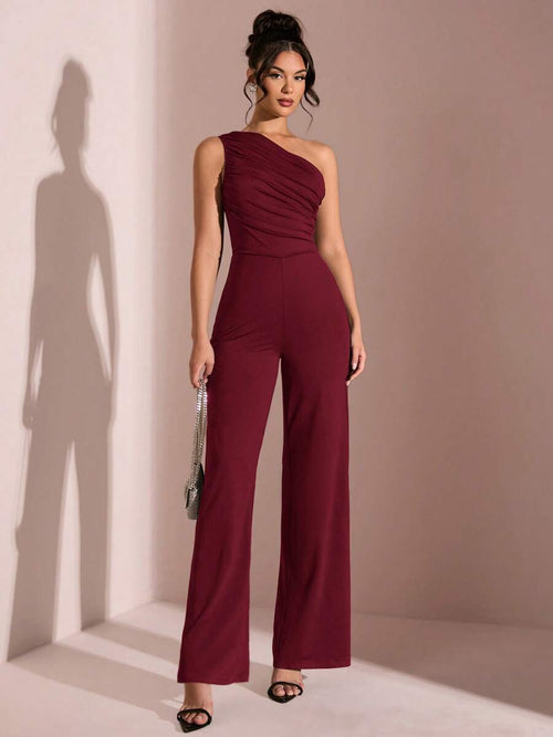 Mujer modelando un jumpsuit elegante color vino de un solo hombro con detalle drapeado.