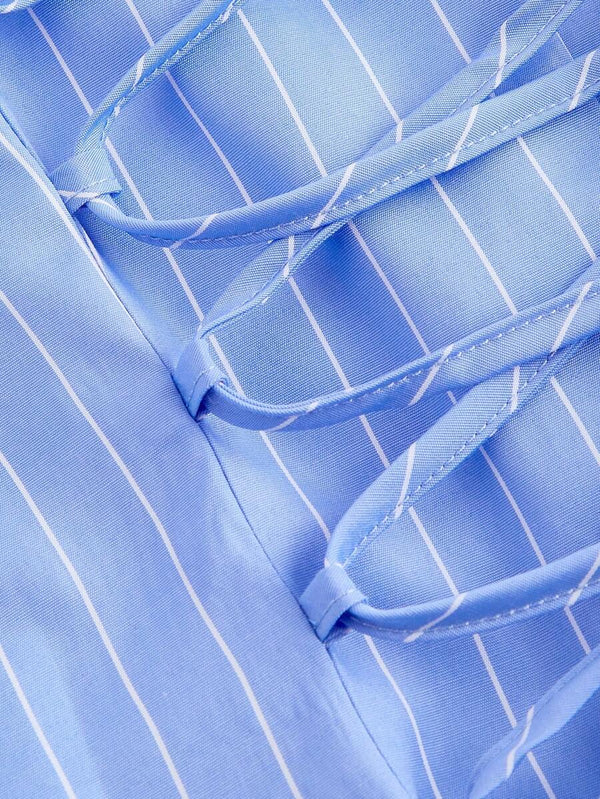 Primer plano de la falda acampanada de un vestido camisero azul y blanco con botones.