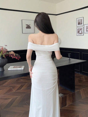 Detalle cercano del escote drapeado y hombros descubiertos del vestido maxi blanco.