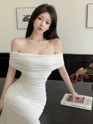 Mano de la modelo sosteniendo un bolso pequeño blanco con lazo, complementando el vestido.