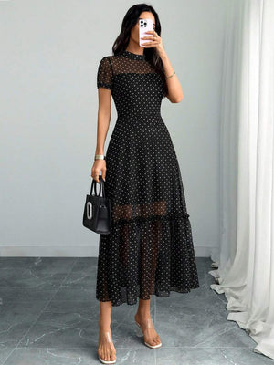 Detalle del bajo del vestido midi negro de lunares con volante y zapatos de tacón negros.
