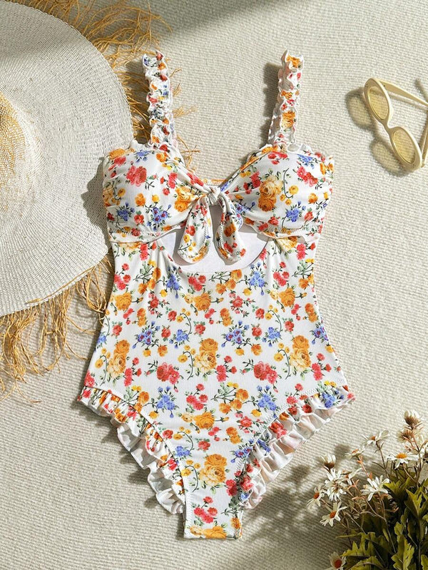 Vista lateral del traje de baño de una pieza con estampado de flores y detalle de cut-out en la cintura.