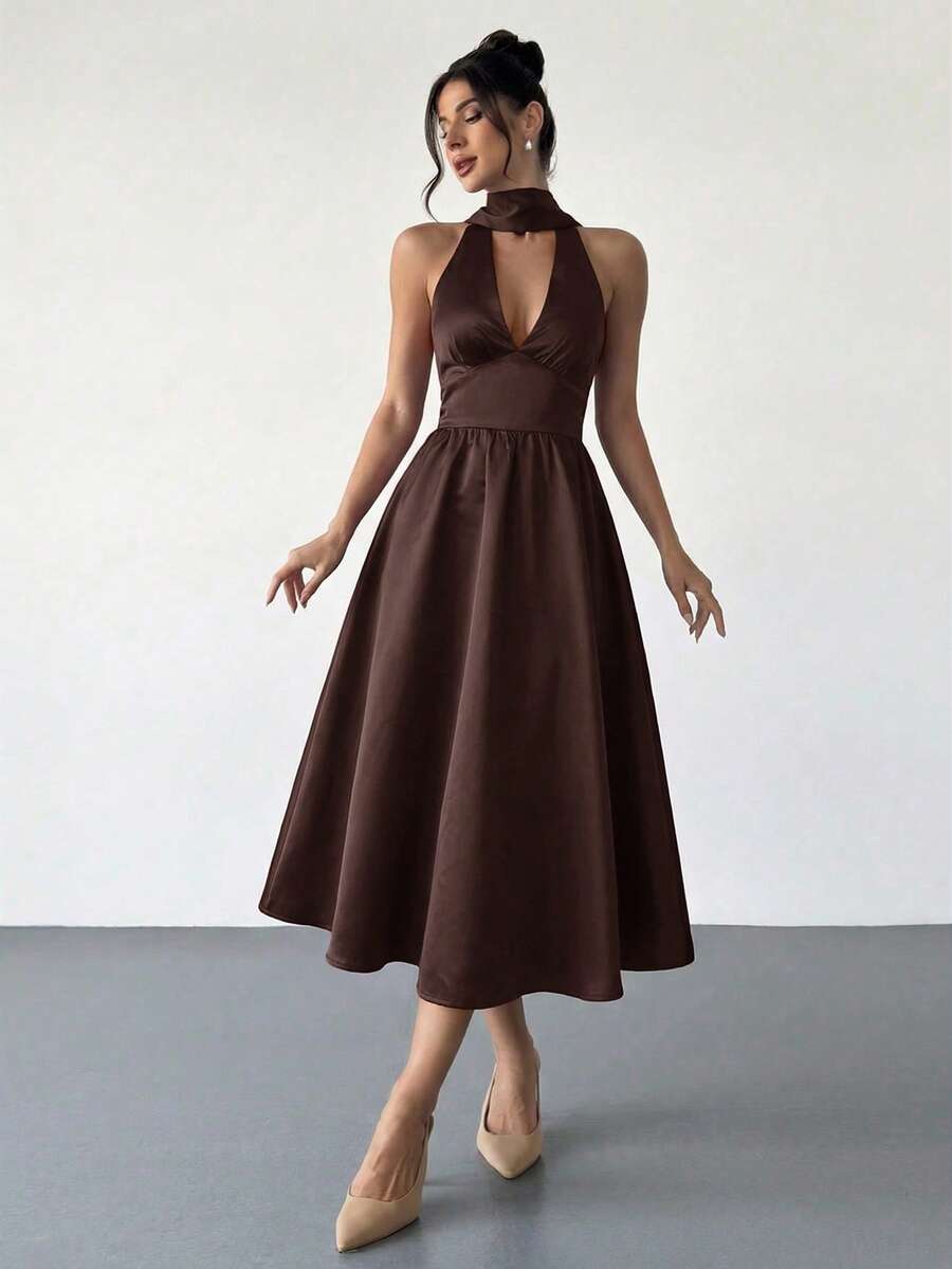 Mujer elegante posando con un vestido halter midi de satén color marrón.