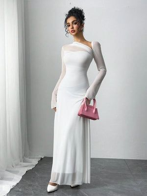 Detalle de la falda fluida de un vestido maxi blanco, la modelo sostiene una cartera rosa.