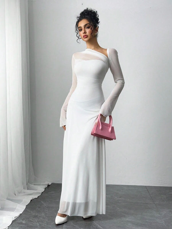 Detalle de la falda fluida de un vestido maxi blanco, la modelo sostiene una cartera rosa.