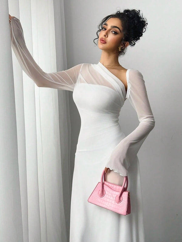 Vista de perfil de una mujer con un vestido blanco largo, posando con zapatos de tacón blancos y una mini cartera rosa.