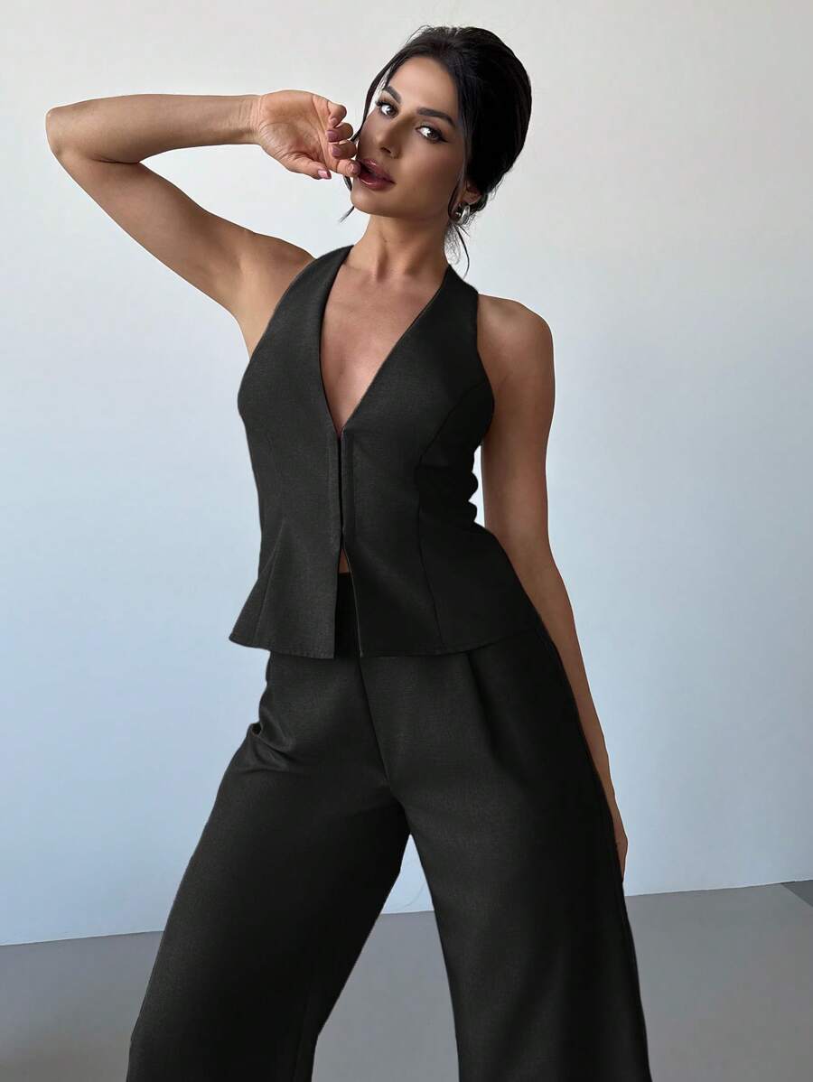 Mujer modelando un conjunto elegante de dos piezas en color negro, compuesto por un chaleco con escote halter y pantalón de pierna ancha.
