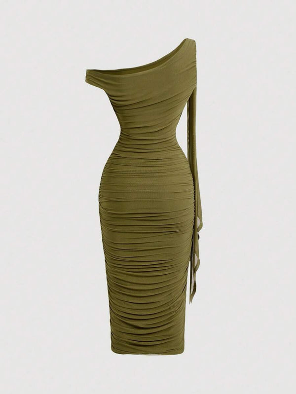 Detalle del escote asimétrico y el aplique dorado en el hombro del vestido verde.