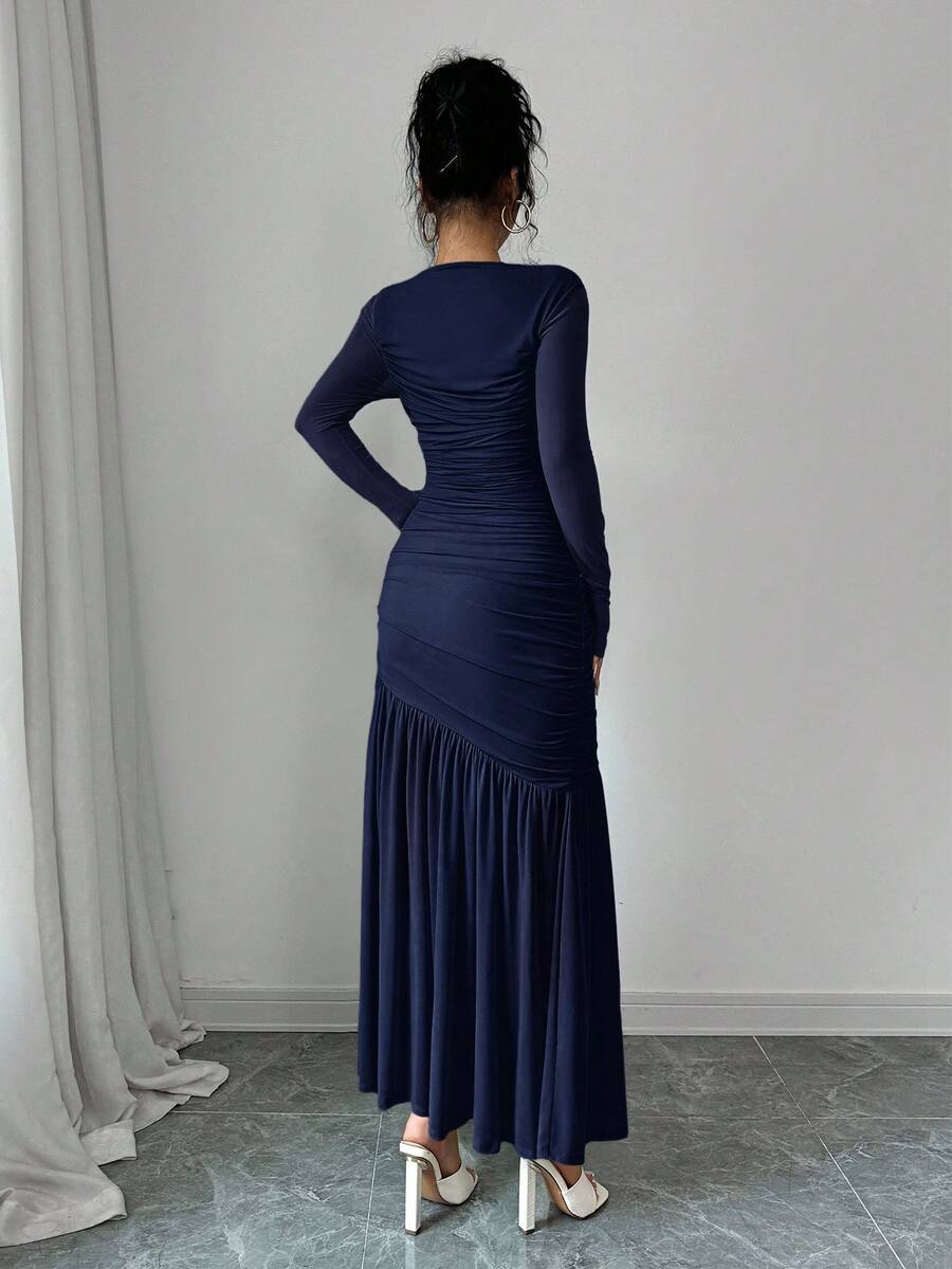 Mujer modelando un vestido largo azul marino de manga larga con detalles fruncidos.