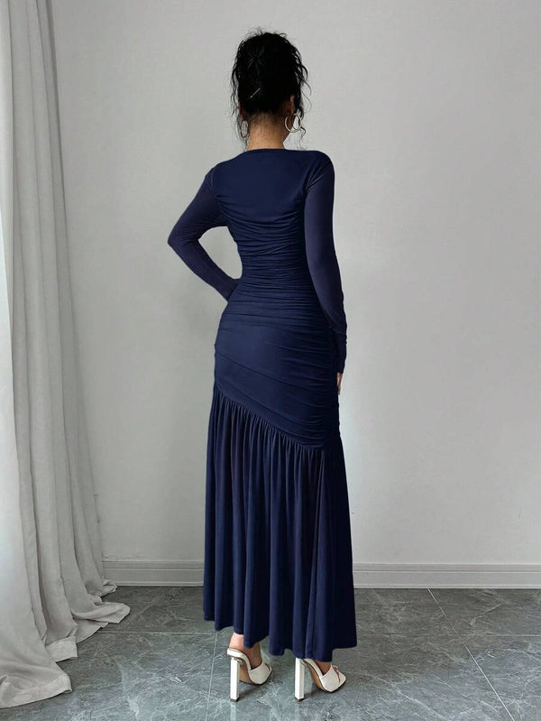 Primer plano del torso de un vestido azul marino con drapeado y manga larga.