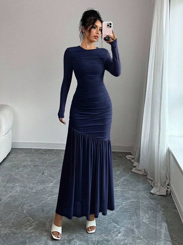 Vista lateral de una mujer con un elegante vestido largo azul marino ajustado al cuerpo.