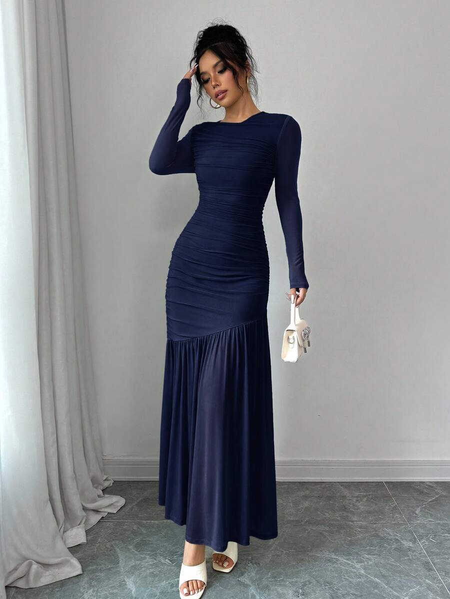 Mujer modelando un vestido largo azul marino de manga larga con detalles fruncidos.