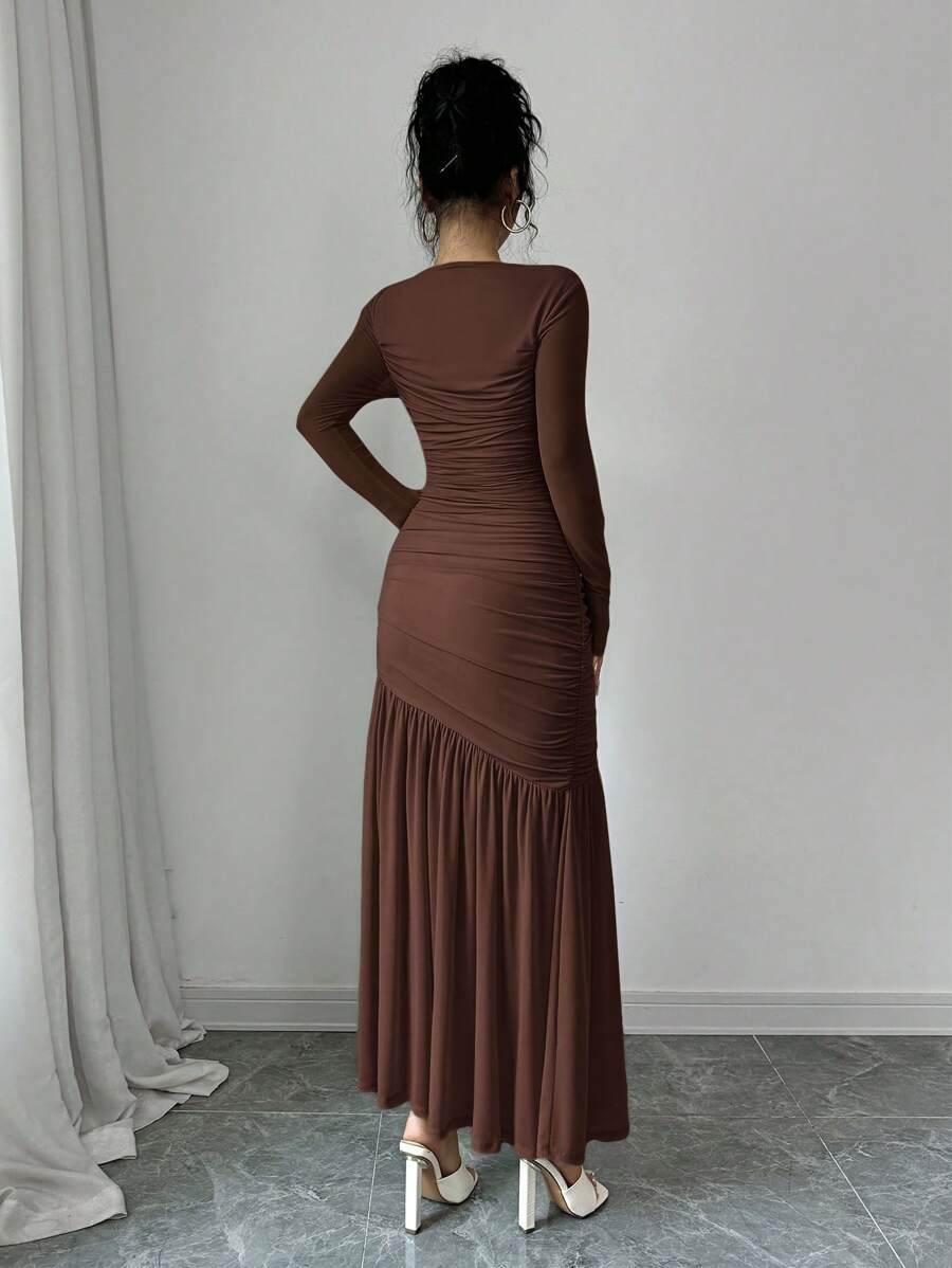 Mujer modelando un vestido largo fruncido de manga larga en color café, vista de cuerpo completo.
