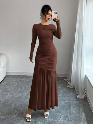 Mujer elegante posando de frente con un vestido maxi ajustado en tono tierra.