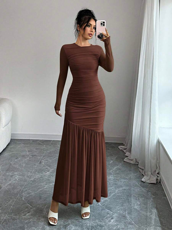 Mujer elegante posando de frente con un vestido maxi ajustado en tono tierra.