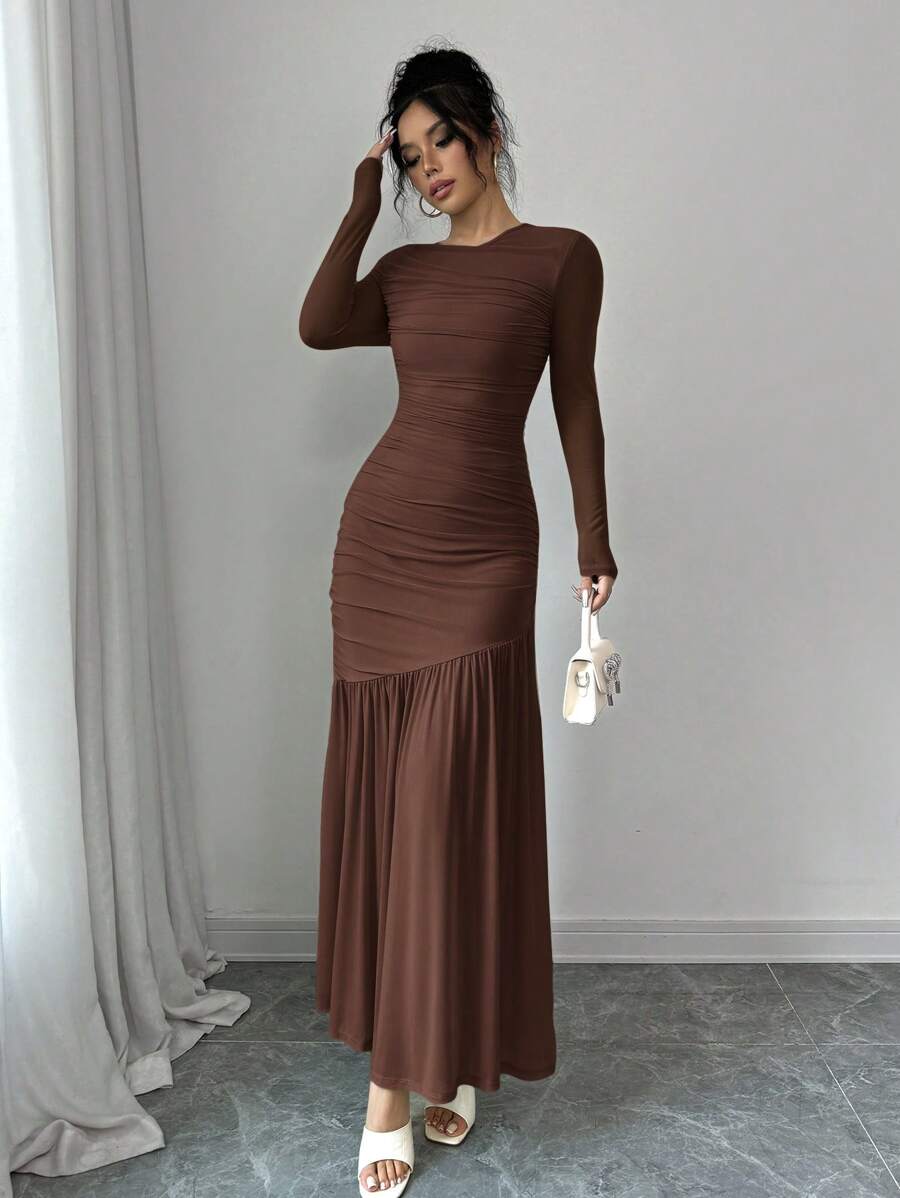 Mujer modelando un vestido largo fruncido de manga larga en color café, vista de cuerpo completo.
