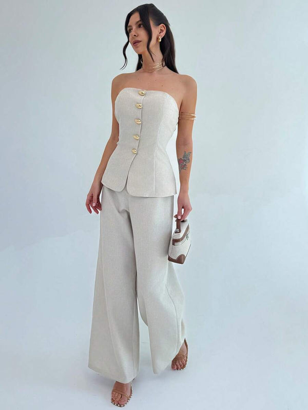 Mujer luciendo conjunto de dos piezas beige elegante con accesorios dorados en un estudio.