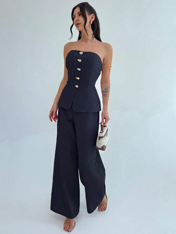 Silueta completa de una mujer vistiendo un conjunto formal de top sin tirantes y pantalón ancho.