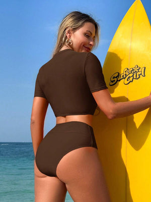 Vista lateral de una mujer usando un bikini deportivo color café de manga corta y talle alto en un día soleado.