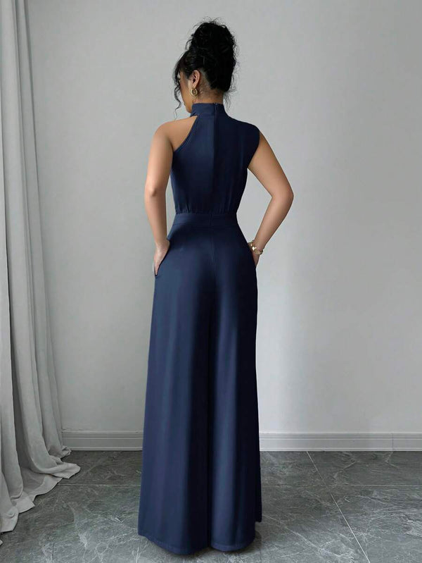 Primer plano del torso de una mujer vistiendo un jumpsuit azul marino con detalle de cuello halter cruzado.