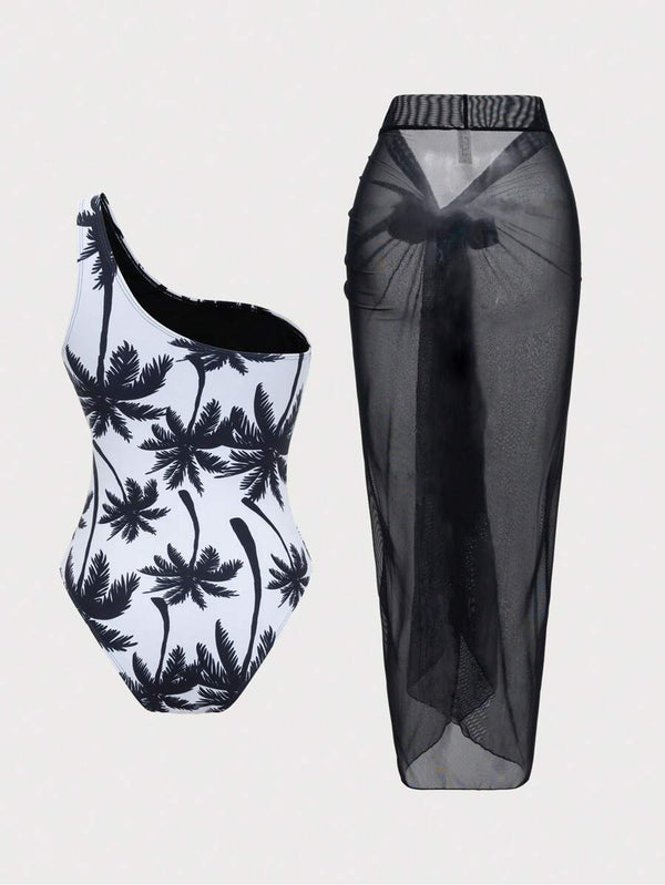 Primer plano del traje de baño de una pieza con escote asimétrico y estampado tropical de palmeras.