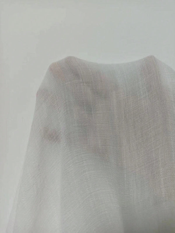 Detalle del tejido semitransparente del conjunto blanco sin tirantes.