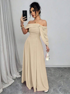 Mujer con vestido largo elegante color albaricoque de hombros descubiertos tomándose un selfie.