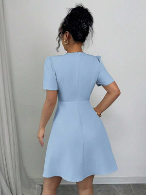 Primer plano del torso de una mujer con un vestido azul cielo de manga corta y escote cruzado.