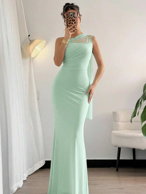 Mujer sosteniendo un bolso blanco mientras viste un vestido de fiesta largo color verde menta.