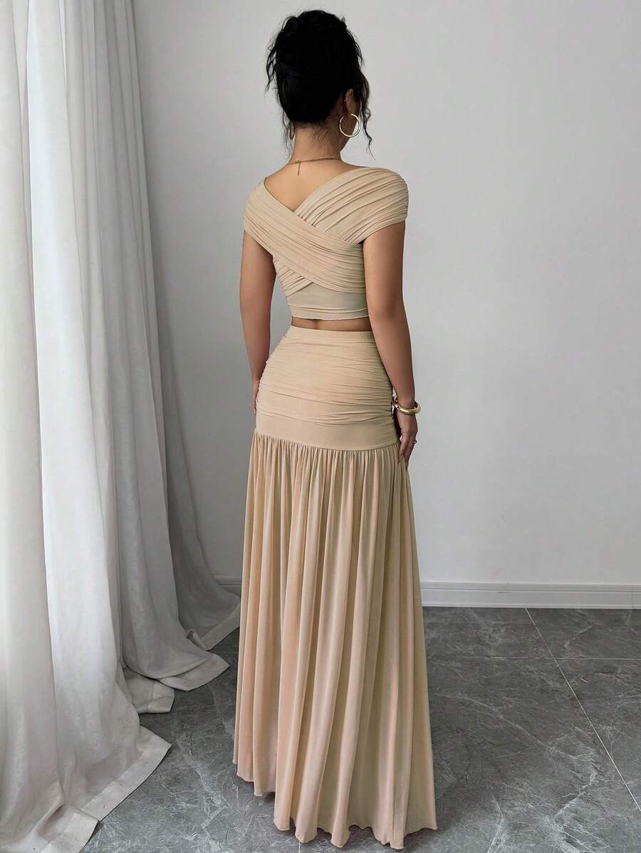 Mujer modelando un conjunto beige de dos piezas con top de hombros descubiertos y falda larga drapeada.
