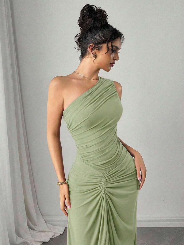 Mujer posando de cuerpo entero con un vestido maxi ajustado de un solo hombro en tono verde claro.