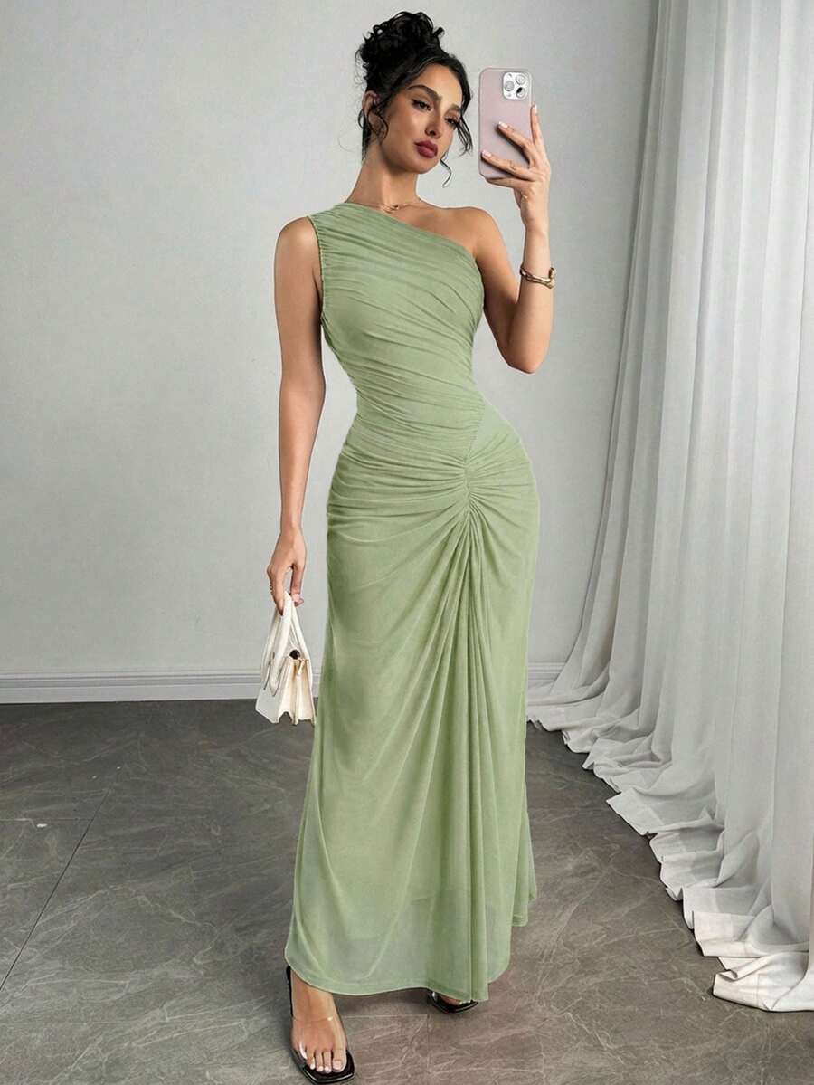 Vista completa de una mujer luciendo un vestido largo asimétrico color verde menta con drapeado en el cuerpo.