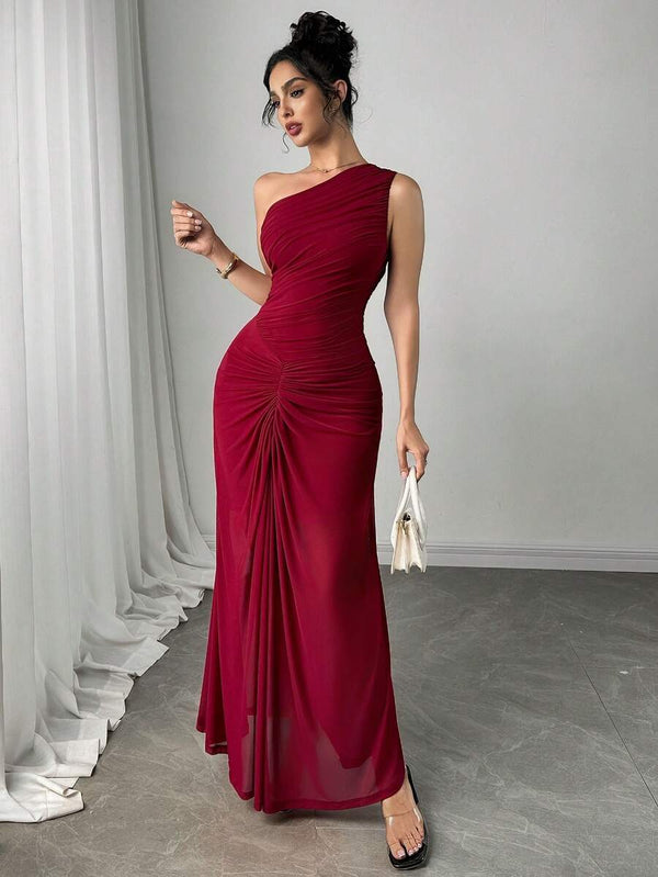 Modelo reflejándose en un espejo, mostrando el diseño de un hombro del vestido maxi color vino y su teléfono.