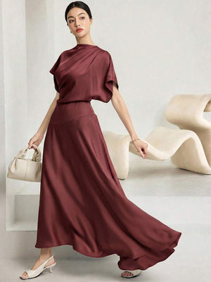 Detalle del escote redondo y pliegues diagonales en vestido maxi de acabado satinado