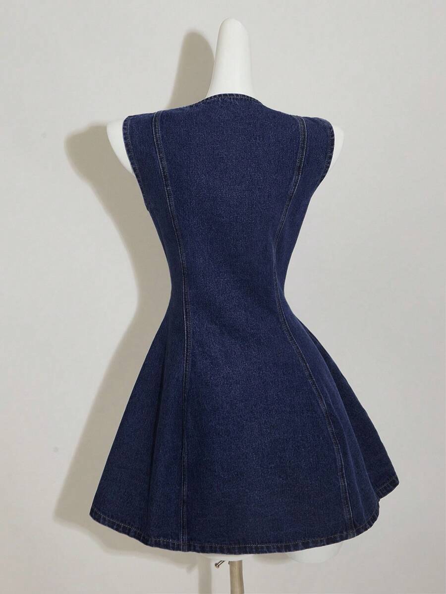 Vista frontal de un vestido de mezclilla sin mangas azul oscuro con botones dorados en un maniquí.