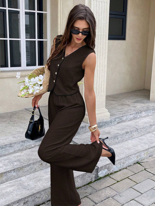 Mujer con conjunto elegante de chaleco y pantalón marrón de pierna ancha posando en escaleras.
