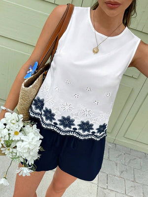 Detalle del bordado floral azul y el bajo festoneado de la blusa blanca.