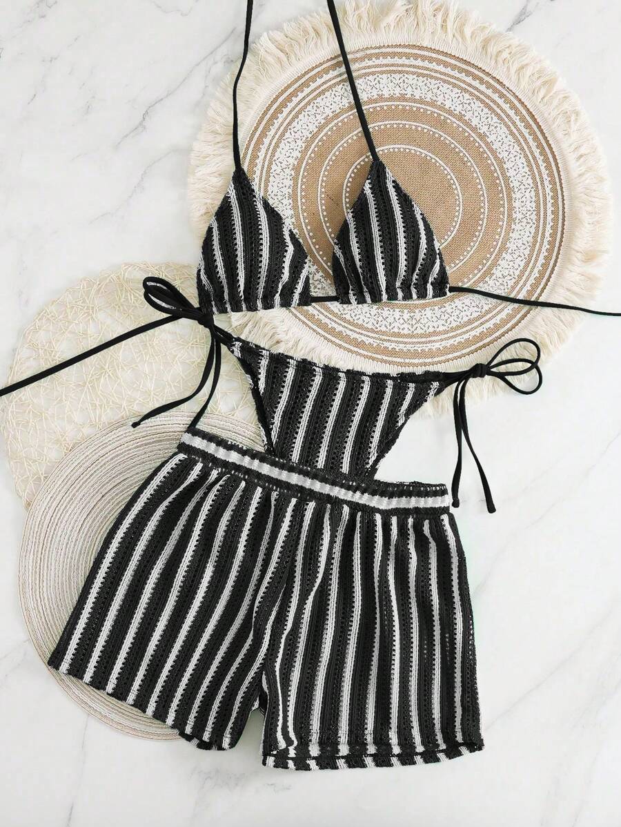 Conjunto de traje de baño de tres piezas a rayas blancas y negras sobre un fondo de mármol.