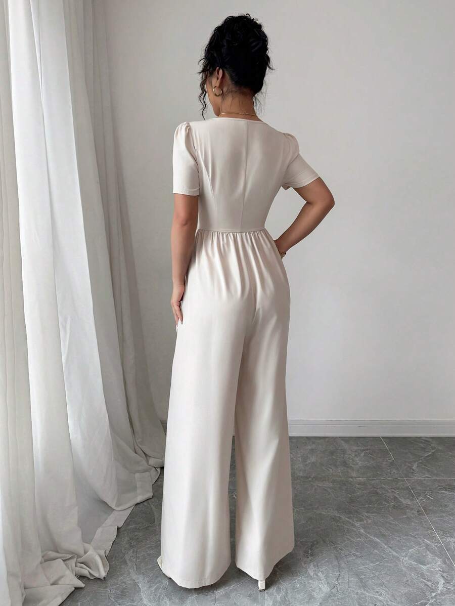 Imagen frontal del mono elegante albaricoque con escote cuadrado y botones.