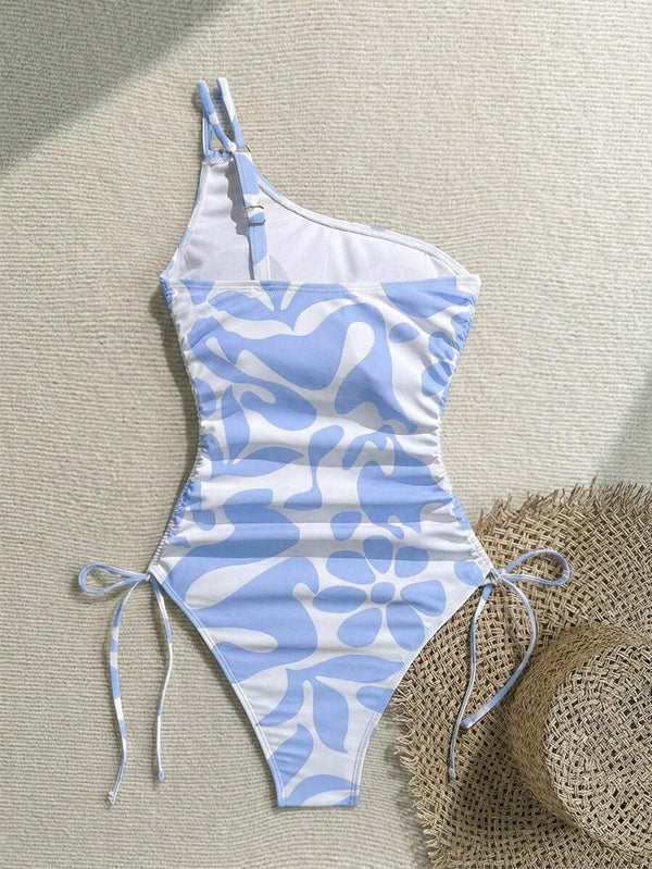 Vista de cerca del escote asimétrico de un traje de baño con tirante doble fino y estampado moderno.