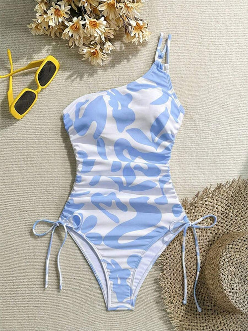 Traje de baño de una pieza con estampado abstracto azul y blanco, diseño de un solo hombro y fruncido lateral ajustable.