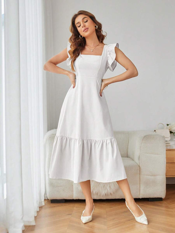 Mujer con vestido blanco midi casual elegante en sala moderna.