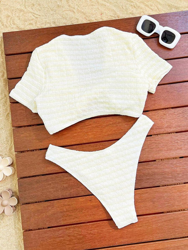 Detalle del top de bikini de manga corta color crema con nudo en el busto y textura a rayas.