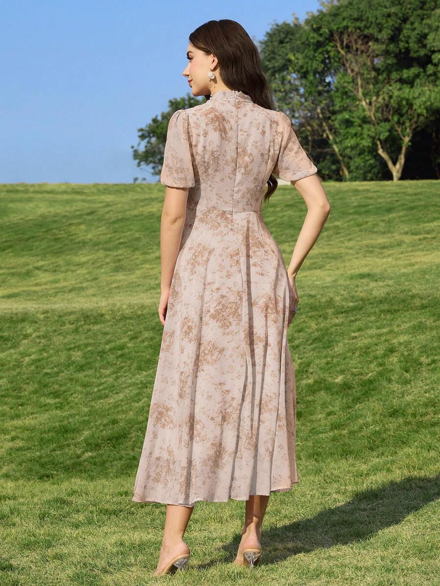 Mujer posando en un campo verde con un vestido midi floral de color beige y lazo al cuello.